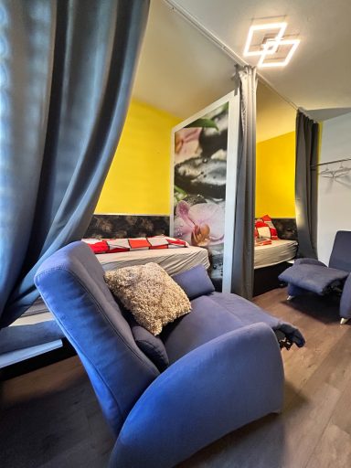 Ein modernes Zimmer mit gelben Wänden, einem blauen Sessel und einem dekorativen Vorhang.